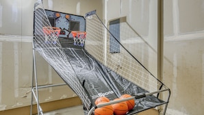 Ein Basketballkorb mit Netz und drei Basketballsäulen in einem Raum mit unbehandelten Wänden.
