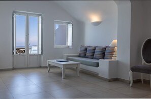 Ein modernes Wohnzimmer mit einem weißen Sofa, einem Couchtisch und Meerblick durch eine Tür.