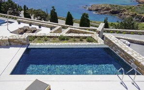 Una piscina con paredes de piedra y vista al mar.