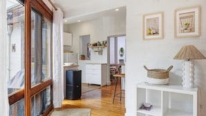 A modern kitchen with white cabinets, a black refrigerator, and a wooden dining table. - The Albert Park Pocket - Stylish Stay with Parking (South Melbourne)