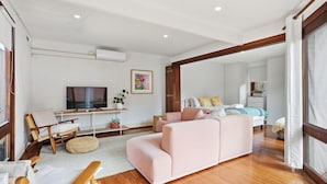 A modern living room with a sofa, TV, and a dining area with a table and chairs. - The Albert Park Pocket - Stylish Stay with Parking (South Melbourne)