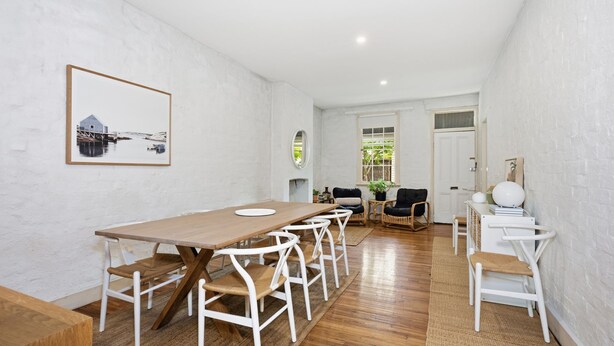 A spacious room with a wooden dining table and white chairs, a cozy seating area with a sofa and chairs, and a large window with a view of greenery. - The Albert Park Pocket - Stylish Stay with Parking (South Melbourne)