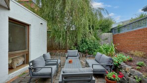 A patio with a sofa set, a table, and a potted plant. - Draper Garden Cottage with Parking (South Melbourne)