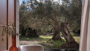 A modern room with a large window, a round table, a cushioned chair, and a tall vase. - Villa Averia, 2BDR, Private Heated Pool, Furnished Terrace, Lefkada (Lefkada)
