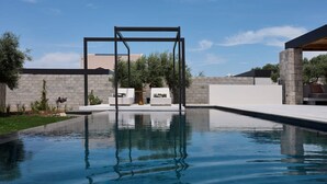A modern outdoor pool area with a metal structure, seating, and a stone wall. - Villa Averia, 2BDR, Private Heated Pool, Furnished Terrace, Lefkada (Lefkada)