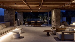 An outdoor patio area with stone walls, wooden furniture, and a ceiling fan. - Villa Averia, 2BDR, Private Heated Pool, Furnished Terrace, Lefkada (Lefkada)