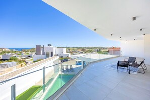 Eine Dachterrasse mit Glasgeländer, einem Pool und einer Sitzgelegenheit mit zwei Stühlen und einem Tisch.