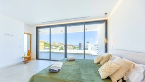 Ein modernes Schlafzimmer mit einem großen Bett, Blick auf die Stadt und einem Balkon.