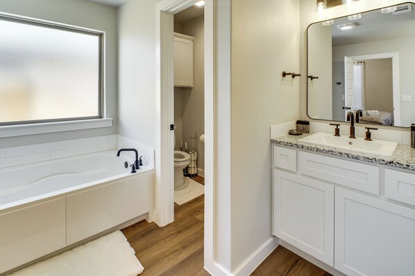 Un baño moderno con bañera, dos lavamanos y un espejo grande.