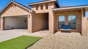 A two-story house with a garage, a covered porch, and a small seating area. - 8 Mi to Ttu! Pet-friendly Home w/ Patio & Yard (Lubbock)