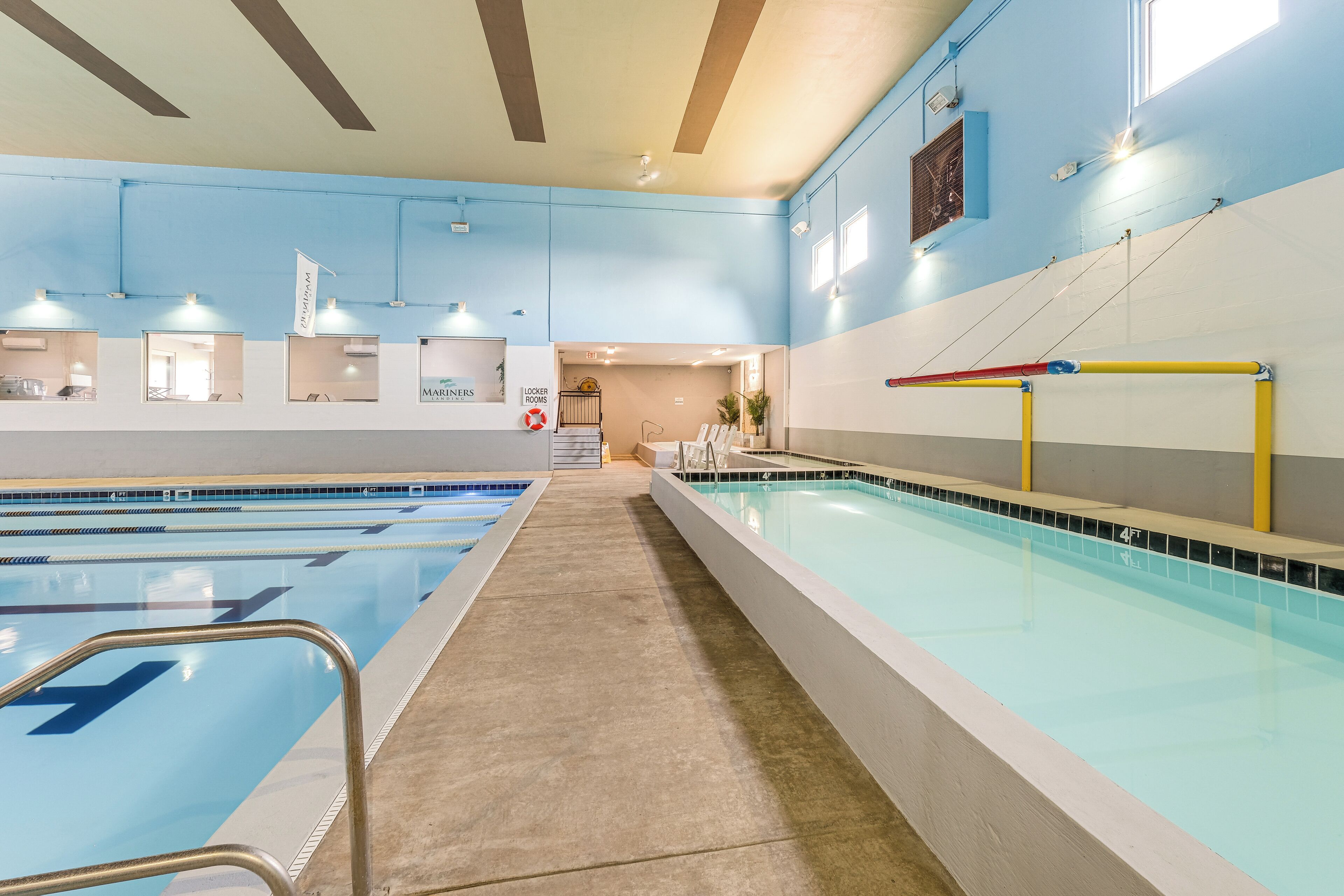 Una piscina interior con carriles delimitados, un puesto de socorrista y una salida visible.