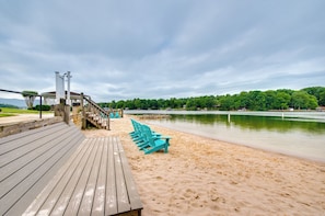 Eine Holzterrasse mit türkisfarbenen Stühlen und einem kleinen Pavillon mit Blick auf einen See.