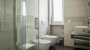 A modern bathroom with a glass shower enclosure, a bidet, a toilet, and a sink with a vanity.