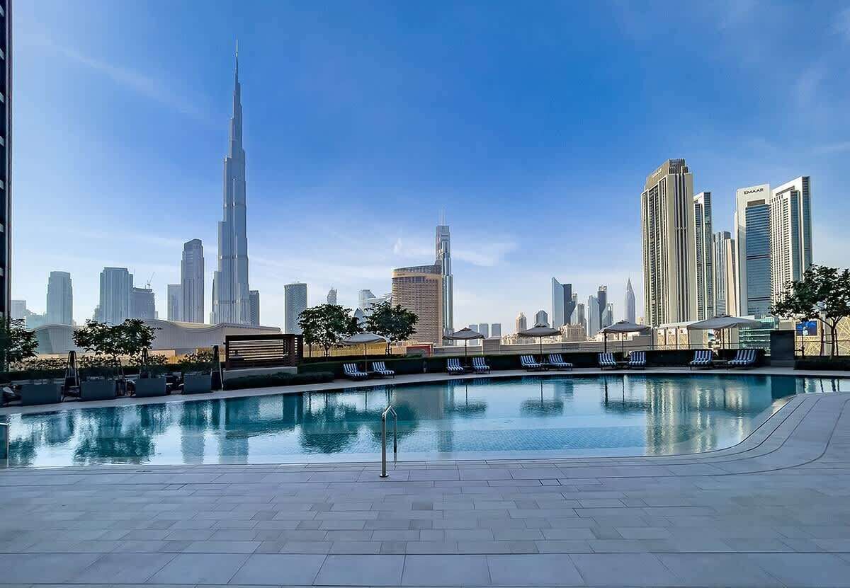 Ein Pool mit Liegestühlen und einer Skyline im Hintergrund.