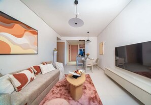 A modern living room with a sofa, coffee table, and a flat-screen TV. - Dubai Mall Apt w/ Burj Khalifa & Fountain Views (Dubai)