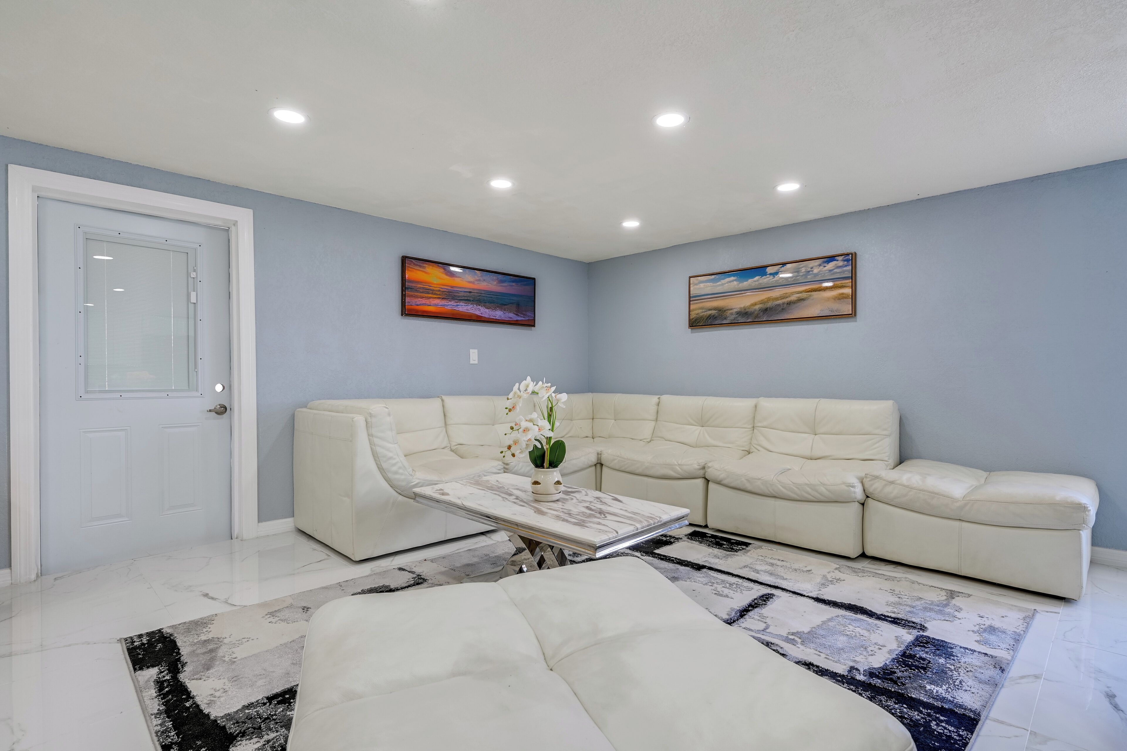 Una sala moderna con un sofá modular, una mesa de centro y dos cuadros en la pared.