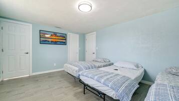 A bedroom with two beds, light blue walls, and a painting on the wall.