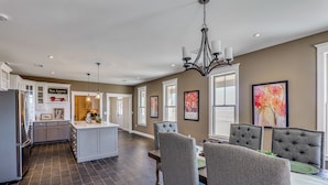 A spacious kitchen with a central island, dark flooring, and a dining area with upholstered chairs and a chandelier. - Peaceful, Serene Getaway 17 Mi to Dtwn Roswell! (Roswell)