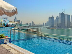 A pool with a city skyline in the background. - Seven Palm - 206 Studio (Dubai)
