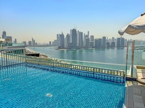 A swimming pool with a view of a city skyline and a body of water. - Seven Palm - 206 Studio (Dubai)