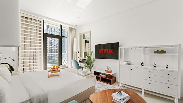 A modern hotel room with a large bed, a desk, a TV, and a wardrobe. - Seven Palm - 206 Studio (Dubai)