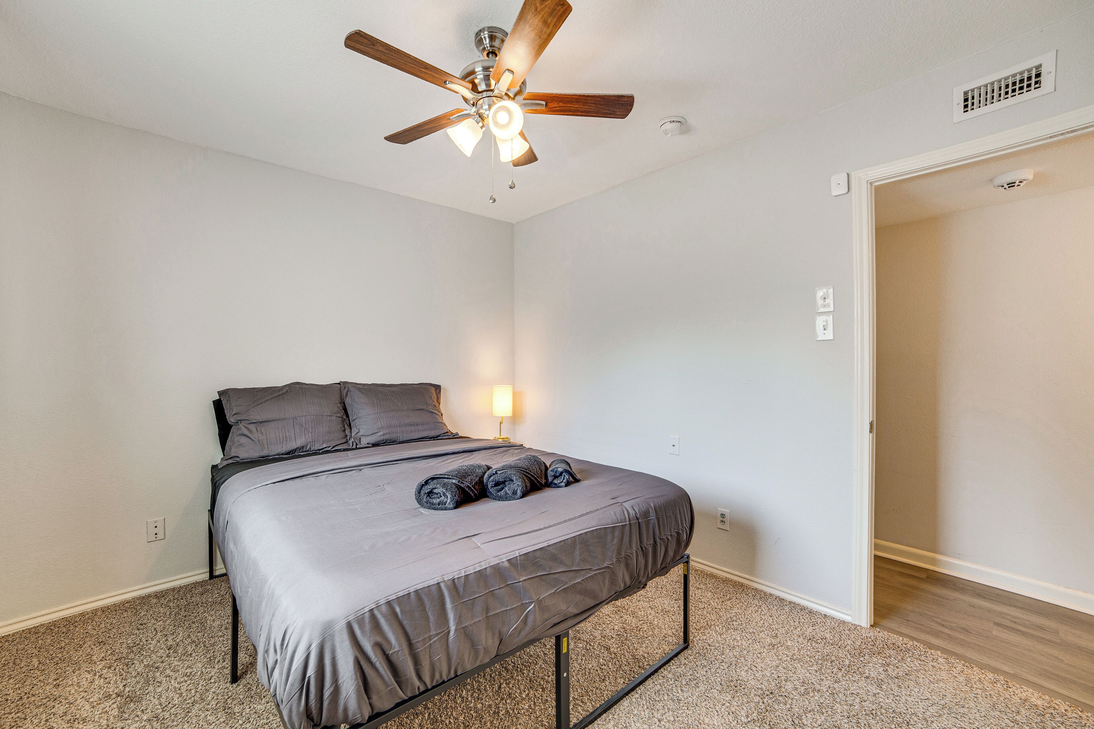 Ein Schlafzimmer mit Bett, Deckenventilator, Nachttisch und Lampe.