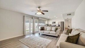 A spacious living room with a large rug, a sofa, and a ceiling fan. - DFW Home Base! Quiet Suburb Stay w/ Yard (Carrollton)