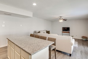 Eine moderne Küche mit Granit Arbeitsplatten, einer integrierten Kochinsel und einem Essbereich mit weißem Sofa und Stühlen.