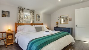 Une chambre à coucher bien rangée, avec un grand lit, une table de chevet avec une lampe, une commode et un miroir.