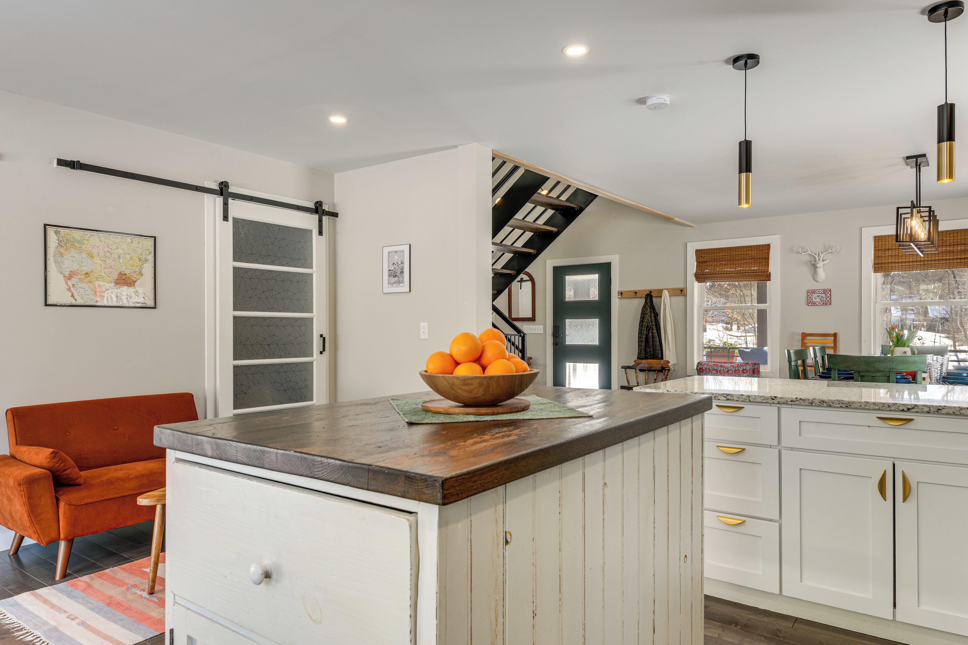 Una cocina con una isla central, armarios blancos y encimera de madera.