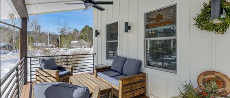 A covered outdoor seating area with wooden furniture and a ceiling fan.