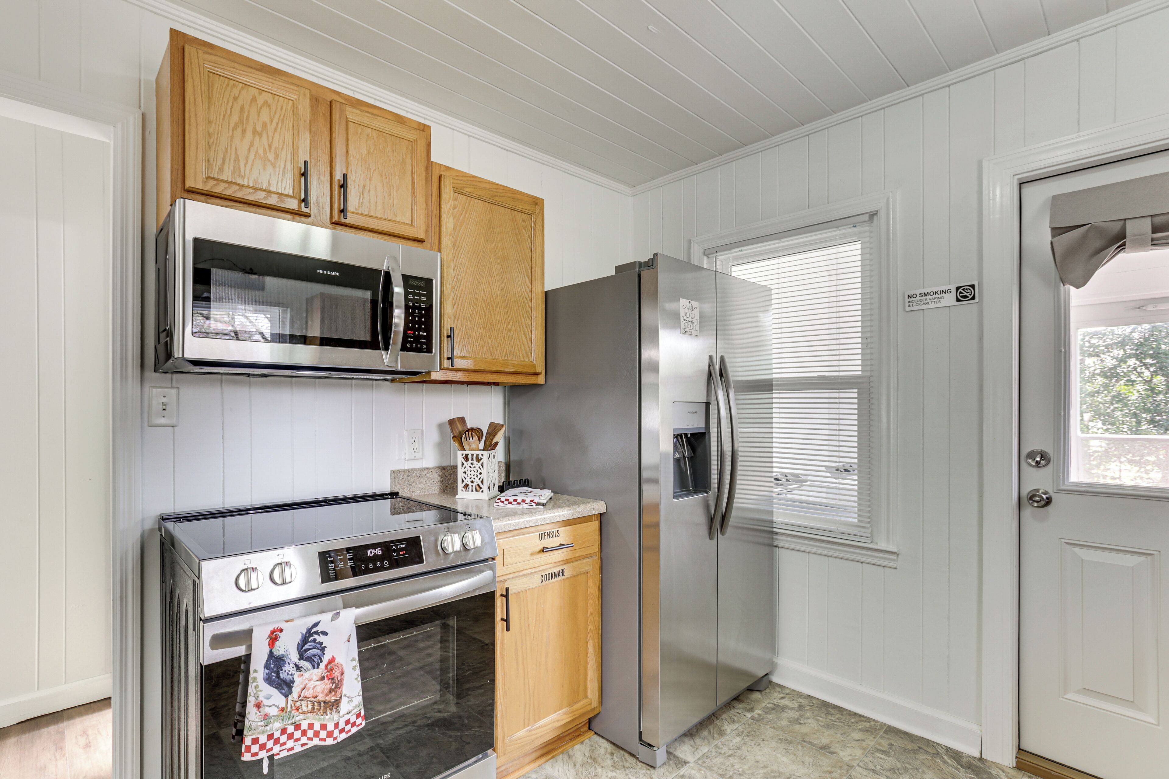A kitchen with wooden cabinets, stainless steel appliances, and a white door with a window.