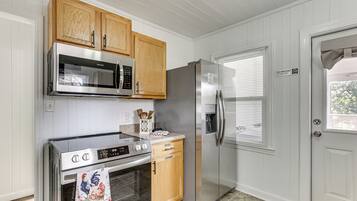 A kitchen with wooden cabinets, stainless steel appliances, and a white door with a window.