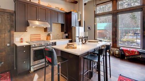 A modern kitchen with dark cabinets, a large island, and a view of the outdoors. - Boulder Dreams Guest House w/ Fire Pit! (McLeod)