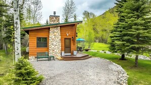A cabin with a stone facade, wooden exterior, and a gravel driveway. - Boulder Dreams Guest House w/ Fire Pit! (McLeod)