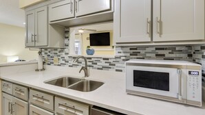 A modern kitchen with white cabinets, a double sink, a microwave, and a tiled backsplash. - Great for Families! Quiet Auburn Getaway w/ Deck (Auburn)