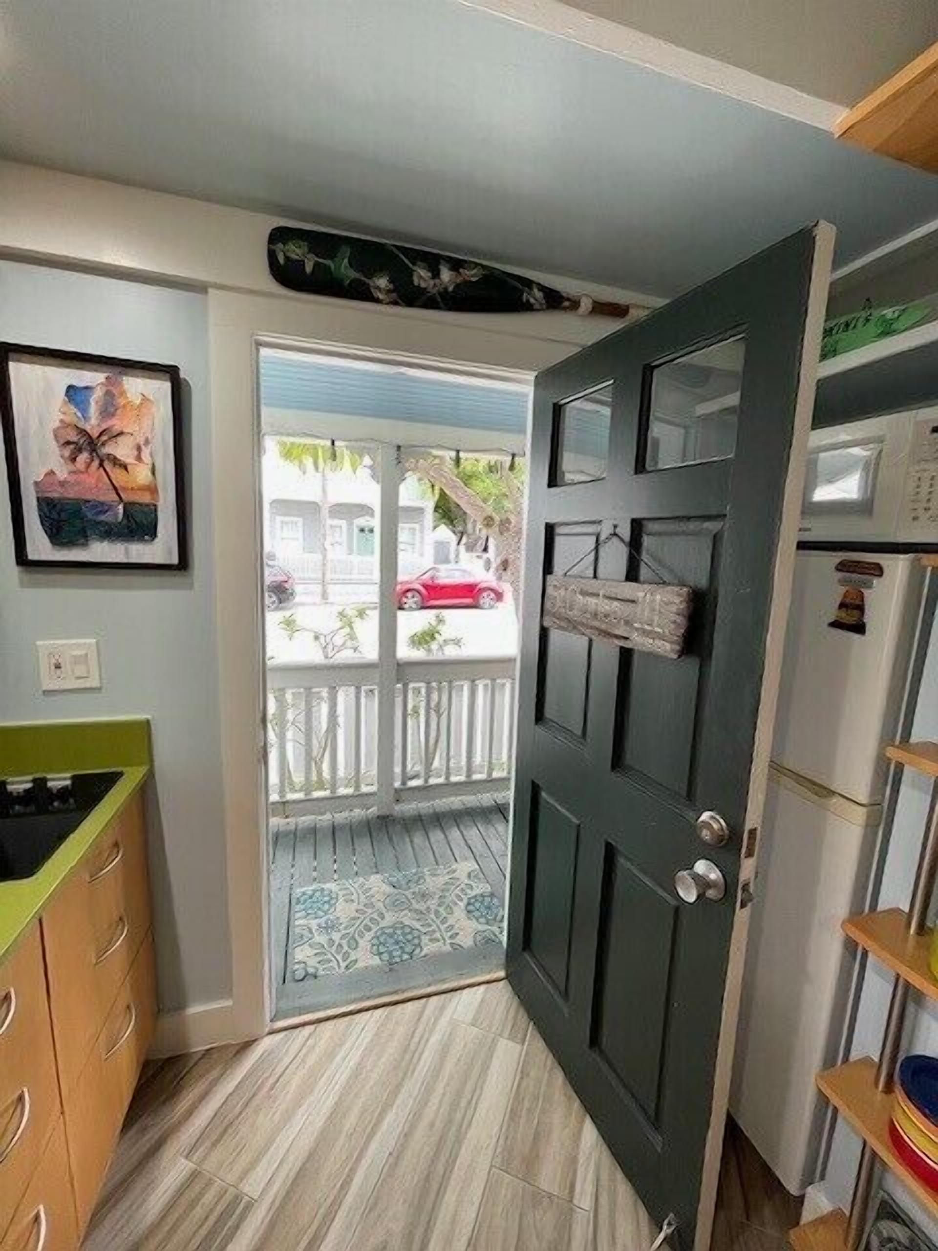 A room with a wooden cabinet, a door leading to a balcony, and a framed picture on the wall.