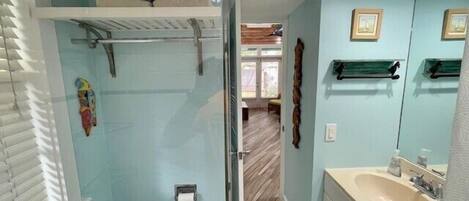 A bathroom with a shower, toilet, sink, and a small window.