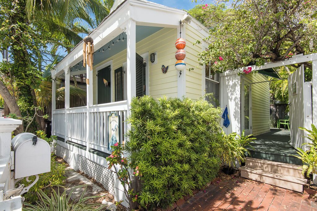 A white house with a porch, a mailbox, and a small garden.