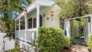 A white house with a porch, a mailbox, and a small garden. - Charming Old Town Studio- Steps to Duval Key West (Key West)
