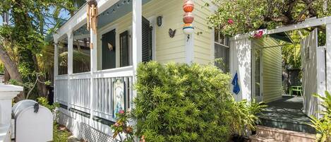 A white house with a porch, a mailbox, and a small garden.