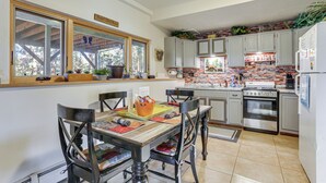Una cucina con tavolo in legno, sedie e una parete rivestita in mattoni.