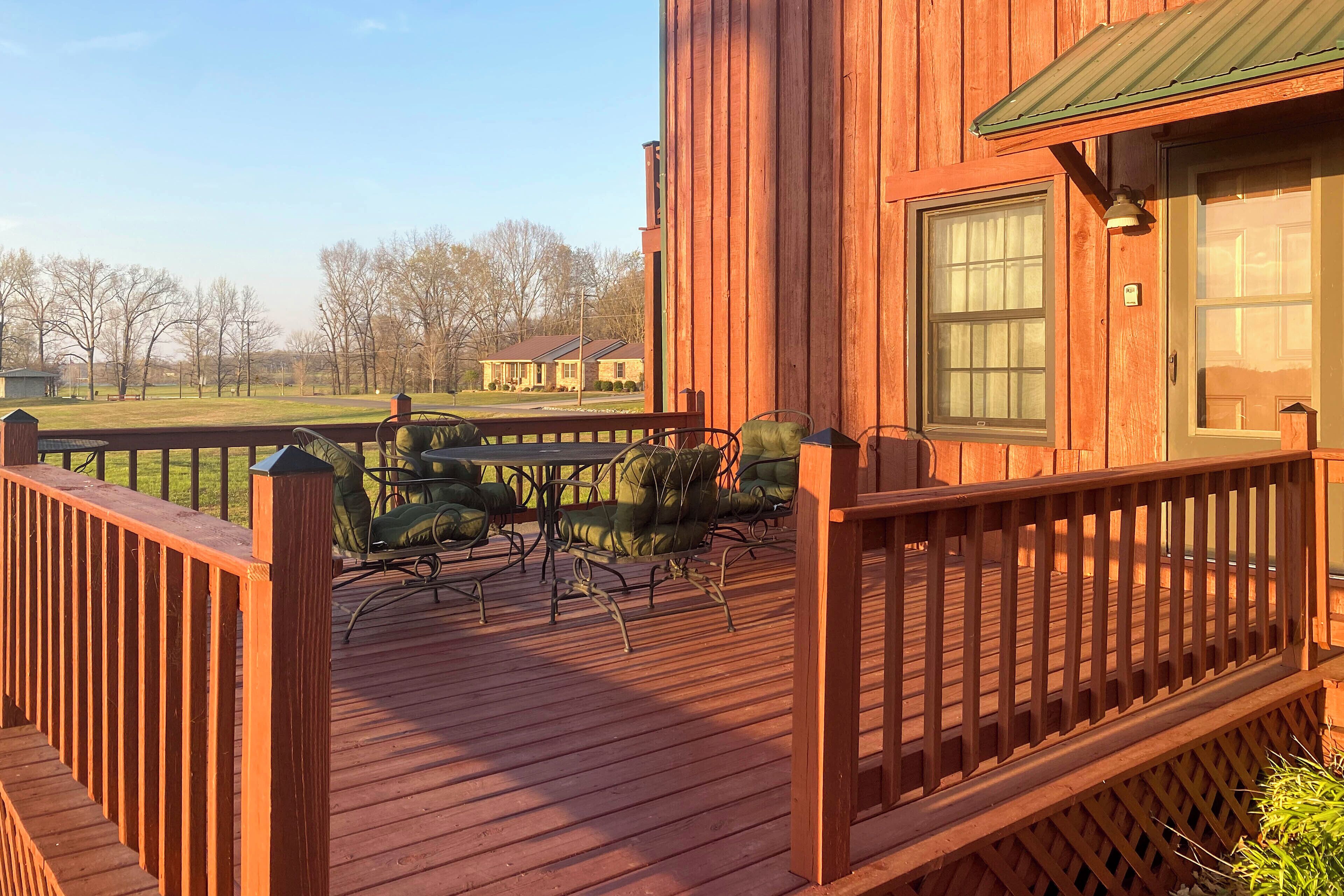 A wooden deck with outdoor furniture and a view of a house in the background.