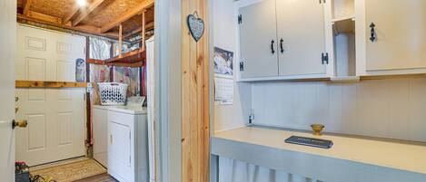 A laundry area with a washing machine, a drying rack, and a heart-shaped decoration on the wall.