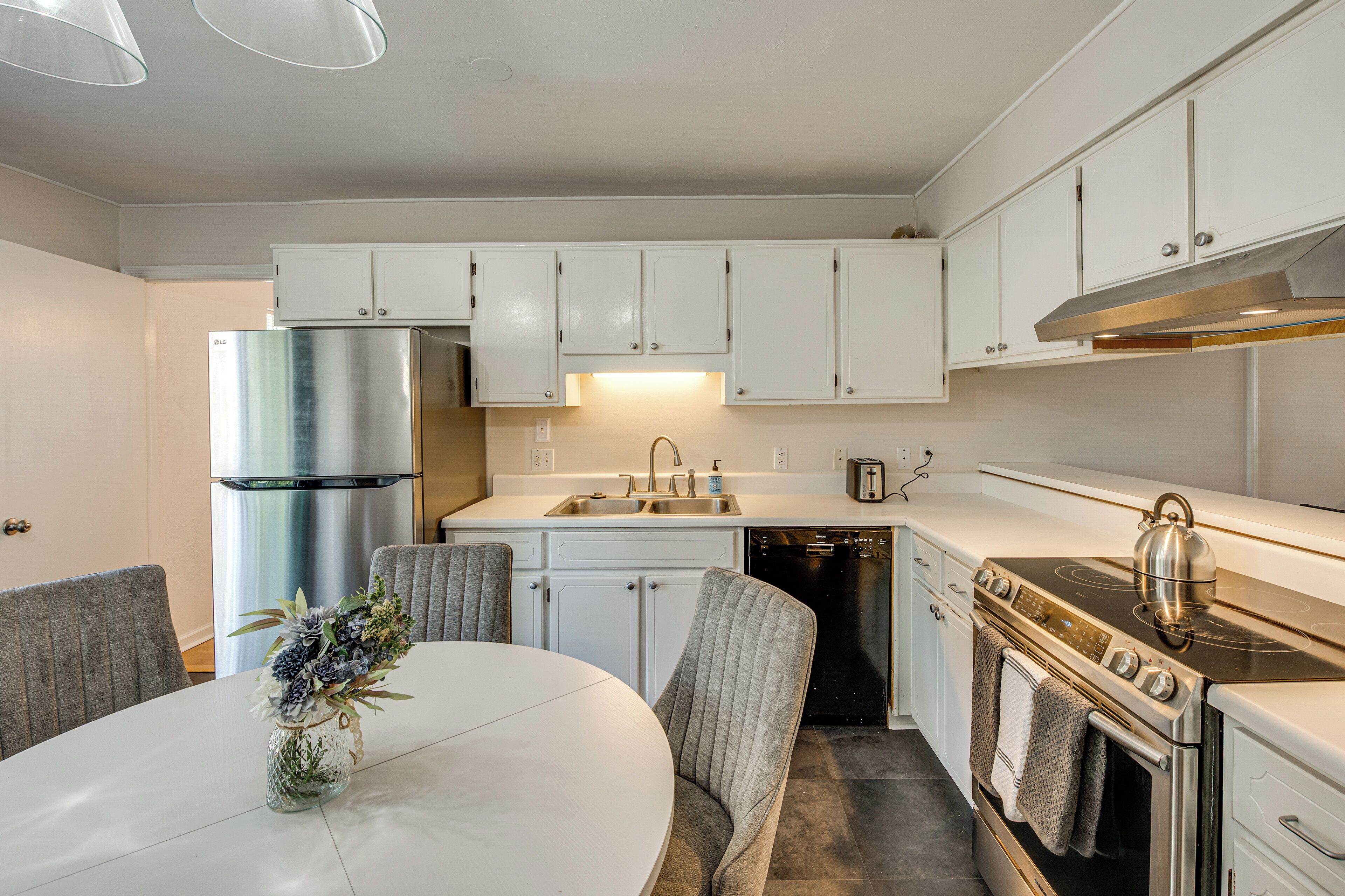Een moderne keuken met witte kasten, een roestvrijstalen koelkast, een vaatwasser en een fornuis.