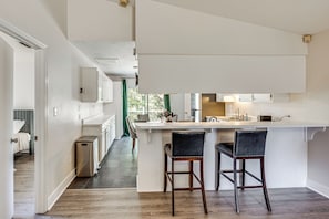 A modern kitchen with a central island, two bar stools, and a view into the adjacent bedroom. - 2 Mi to Fsu: Pet-friendly Retreat w/ Private Yard (Tallahassee)