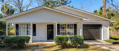 A single-story house with a covered porch, a garage, and a well-maintained lawn.