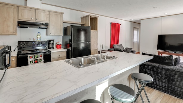 A modern kitchen with a central island, stainless steel appliances, and a large TV in the living area. - 2 Mi to Lake Marion! Pet-friendly Home w/ Yard (Santee)