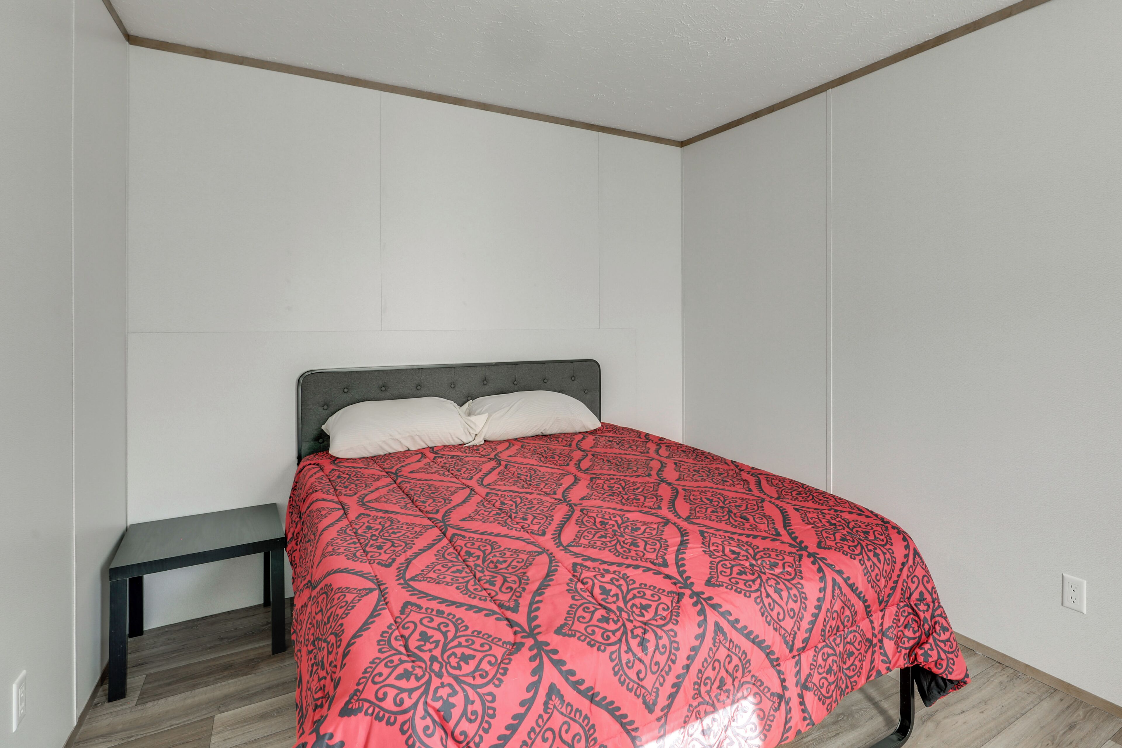 Une chambre à coucher avec un lit, un banc et un mur uni.