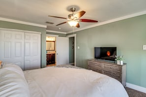 A bedroom with a bed, a ceiling fan, a dresser, and a TV. - Beach Getaway on Mustang Island: Pet Friendly! (Port Aransas)